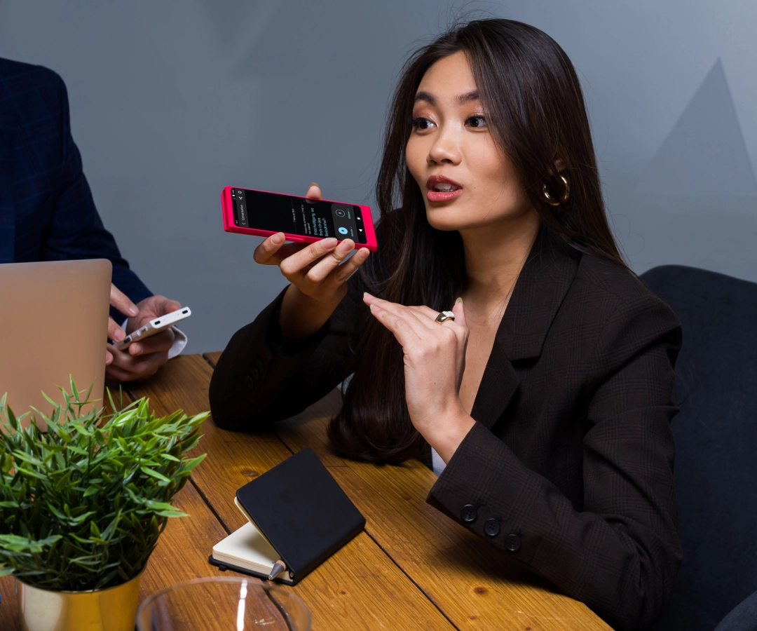 Ein Mann hält einen Übersetzer in der Hand und ist von Freunden umgeben. Im Hintergrund ist historische Architektur sichtbar