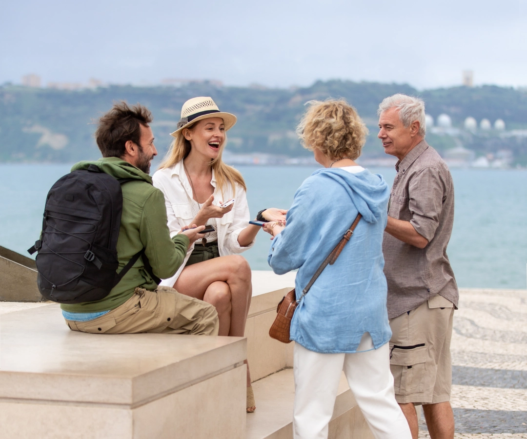 Eine Person mit roten Haaren und einem Blumentattoo auf dem Arm hält ein grünes digitales Gerät hoch und zeigt damit auf eine Anzeigetafel mit verschiedenen Postern und Veranstaltungsinformationen.