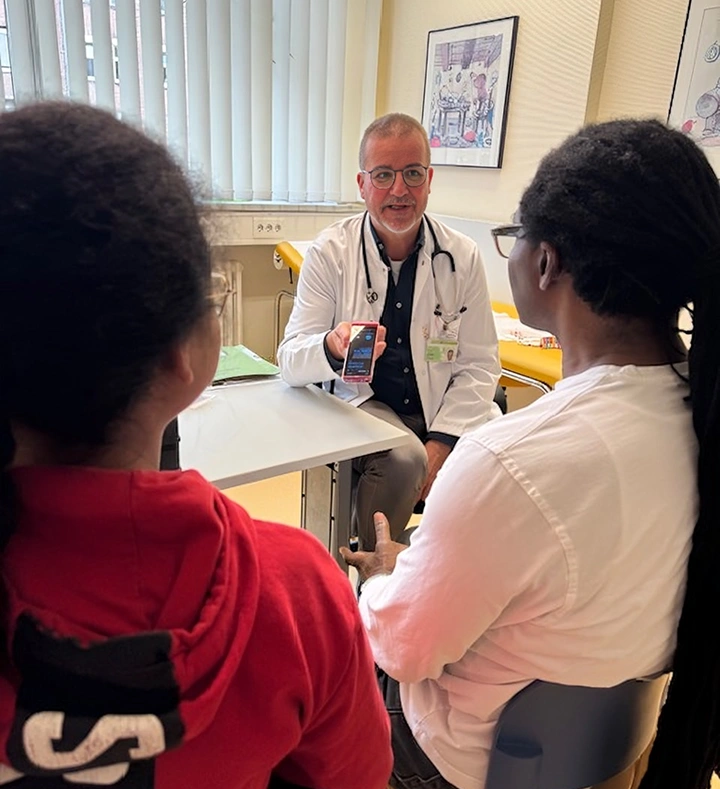 Ein Arzt erklärt Eltern mit einem kleinen Kind in einer Gesundheitseinrichtung etwas.