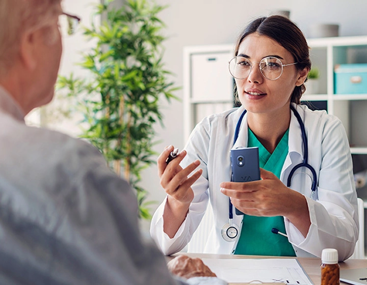 Eine Ärztin unterhält sich in der Sprechstunde über den Vasco Translator V4 mit einem Patienten.