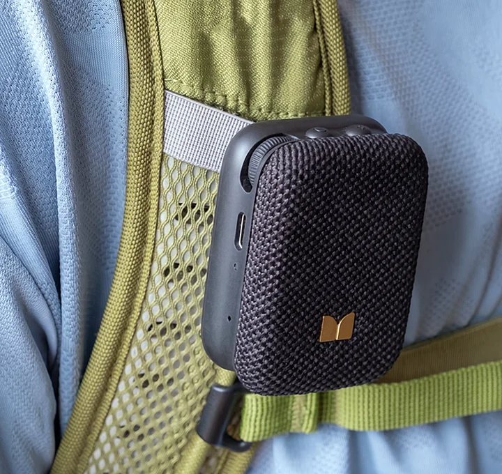 Schwarzer Mini-Bluetooth-Lautsprecher, befestigt am olivgrünen Gurt eines Rucksacks